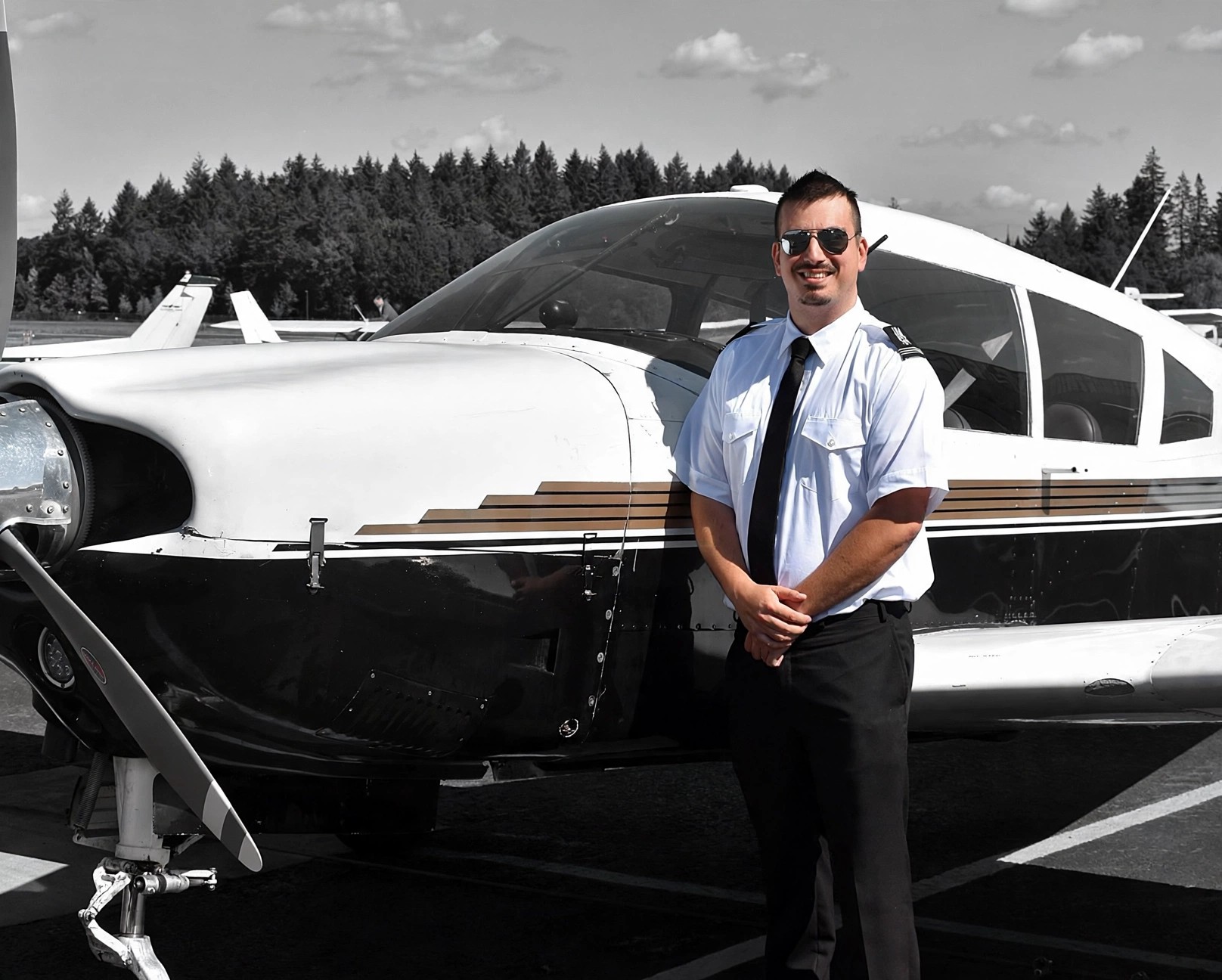 Kenneth Berry in pilot uniform standing beside a single-engine aircraft on the ramp