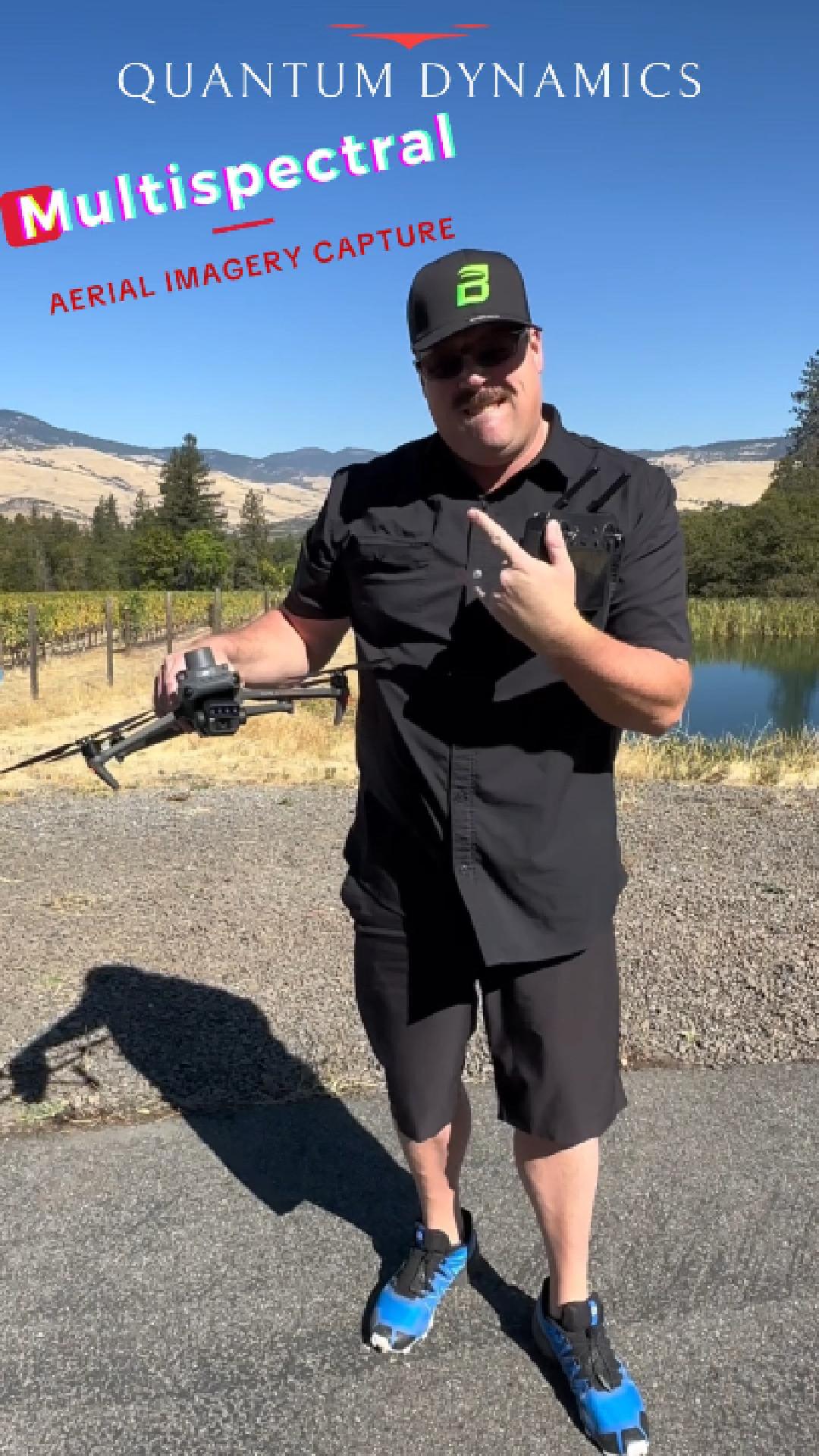 Sean Holt holding a multispectral drone in Oregon vineyard country, with a pond and hills behind him, for Quantum Dynamics multispectral aerial imagery capture