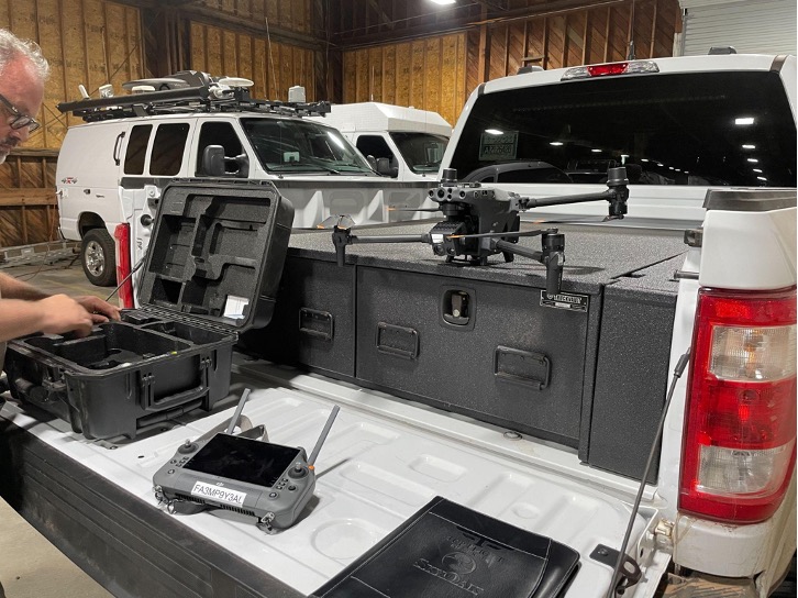 Enterprise drone staged on a pickup truck bed storage system in the hangar, controller and hard case beside it, ready for a job
